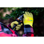 Hands wearing yellow-green JustForKids gloves trimming foliage with garden shears in an outdoor setting