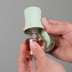 Hands inserting a fragrance bottle into a soft sea glass Mainstays plug showing assembly