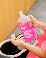 Close-up of hands holding and pouring The Pink Stuff Miracle All Purpose Floor Cleaner into a measuring cup over a mop bucket