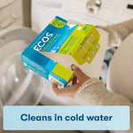 Lifestyle image of hands pulling a laundry detergent sheet from an ECOS box over a washing machine