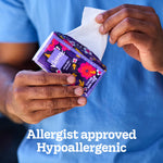 Hands pulling a tissue from a small purple floral Kleenex On-The-Go pocket pack with 'Allergist approved Hypoallergenic' text below