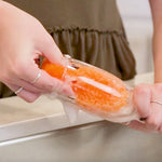 Hands wringing or squeezing an orange Scrub Daddy sponge under running water creating suds