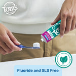 Close view of hands squeezing Tom’s toothpaste onto a toothbrush above a sink with fluoride and SLS free badge