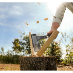 HATchet splitting wood on a stump outdoors with wood chips flying, showing a HART hatchet in use