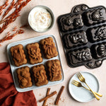 Styled overhead of baked mini loaves beside Nordic Ware harvest mini loaf pan and bowl of whipped cream