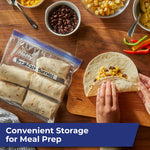 Meal-prep scene with a Hefty labeled freezer bag of breakfast burritos beside a hand assembling a tortilla