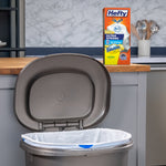Kitchen scene with an open gray trash can lined with a white Hefty bag and a Hefty Fabuloso lemon box on the counter