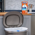 Hefty Ultra Strong product box displayed on a kitchen counter near an open trash can lined with a white drawstring bag.
