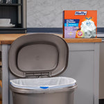 Kitchen scene with an open trash can lined with a white bag and a Hefty Ultra Strong box displayed on the counter behind it.