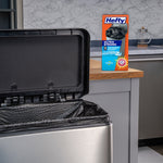 Kitchen scene with a stainless steel trash can lined with a textured black bag and a Hefty product box on the counter