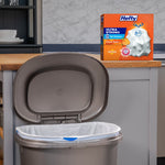 Kitchen scene with a grey trash can lined with a white Hefty bag and a Hefty Ultra Strong orange box on the counter