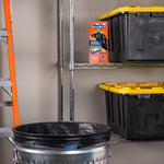 Storage-shelf scene showing a Hefty Ultra Strong trash bag box beside bins and a metal trash can lined with a black bag