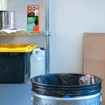 Hefty trash bag box placed on a metal shelving unit with a lined trash can in foreground in a storage setting