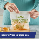 Hands holding a Hefty compostable press-to-close bag with fruit pieces inside on a countertop