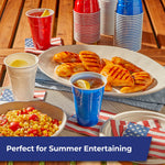 Outdoor entertaining scene with Hefty solid red, white and blue cups on a table near plated grilled food and sides