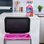 Kitchen scene with open stainless step trash can lined with a bright pink Hefty trash bag and product box on counter