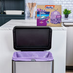 Open stainless kitchen trash can lined with a purple Hefty trash bag and Hefty product box on the counter behind it