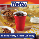 Red Hefty cup filled with a dark beverage on a table with chips and pretzels, Hefty logo above