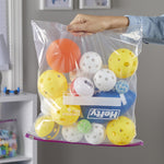Hand holds a clear Hefty slider storage bag filled with assorted plastic balls and a visible Hefty logo