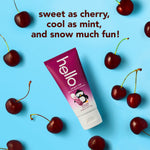 Tube of hello Penguin Chill cherry mint toothpaste surrounded by fresh cherries on a blue background with playful slogan text.