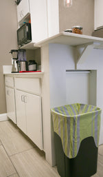 Kitchen scene showing a trash can lined with a yellow-and-white striped Hero scent stripes bag under a counter