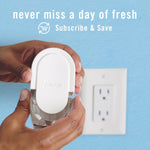 Hands holding a Febreze plug-in refill near an outlet with text encouraging Subscribe & Save for regular deliveries