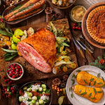 Overhead styled holiday table with carved ham and sides, showing a roasted main beside other dishes