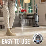 Lifestyle image of person sprinkling Hoover carpet powder onto carpet with an upright vacuum in background