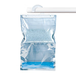 Clear hanging moisture-absorber bag with blue desiccant crystals and white plastic hanger on a white rod