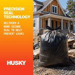 Black tied contractor trash bag in front of a house-under-construction with Husky logo and precision seal technology text