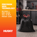 Lifestyle-style image of a tied black trash bag in a garage with Husky branding and precision seal text