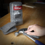 Hyper Tough packaged steel wool with pads and a hand using a pad to clean a hammer head on a wood surface