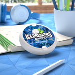 Ice Breakers coolmint puck shown in a tabletop lifestyle setting with headphones, notebook and a pen nearby