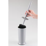 Hand lifting a silver toilet brush handle from its matching cylindrical holder, showing the black bristle head inside the cup.