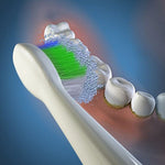 Illustration of a toothbrush head brushing teeth with foamy particles targeting plaque at the gumline.