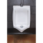 Installed white urinal with a tri-lobed plastic screen seated in the drain area against a tiled wall