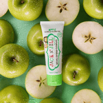 Jack N' Jill apple toothpaste tube styled on a background of whole and halved green apples