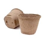Two unplanted compressed peat pots on a white background, showing textured biodegradable material and drainage holes
