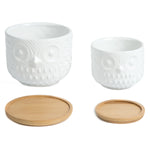 Two white ceramic owl planters from K‑Cliffs with separate round bamboo saucers placed below each pot on a white background.