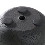 Close-up of the bottom of a textured black mini cement planter showing a central drainage hole and three adhesive felt pads.