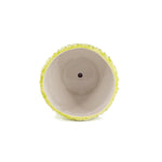 Top-down view into a K-Cliffs lime-yellow floral ceramic planter showing interior and central drainage hole on white background.