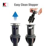 Two black plastic drain assemblies showing removable stopper being lifted for cleaning