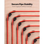 Red PEX pipes routed around corners held by black 90-degree bend supports mounted on wood