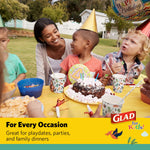 Children at a birthday party seated at a table using dinosaur-print Glad paper cups and party supplies