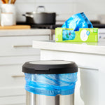 Kitchen scene with a stainless trash can lined with a blue bag and a Great Value green box on the counter