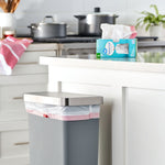 Kitchen scene with a gray trash can using a white drawstring bag and the Great Value trash bag box on the counter