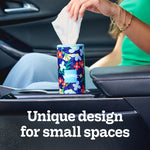 Kleenex Perfect Fit floral tissue canister placed in a car cupholder with a hand pulling a tissue from the top.