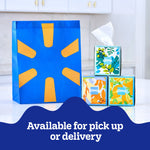 Three decorative Kleenex cube boxes stacked beside a blue and yellow retail bag with 'Available for pick up or delivery' text