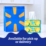 Two decorative Kleenex boxes with tissues next to a blue and yellow reusable shopping bag and pickup text