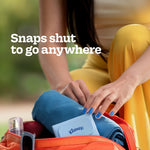 Woman placing a blue Kleenex Snap & Go case into a bag with text ‘Snaps shut to go anywhere’